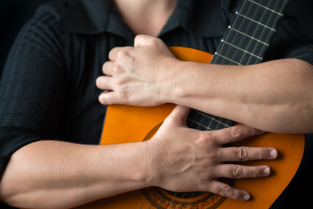 Classic guitar closeup - Musician hands embracing a classic acoustic guitar