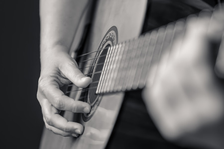 Acoustic guitar detail on black and white - Musician hands playing a classic guitar isolated on a black backgroundの写真素材