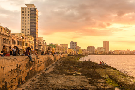 HAVANA,CUBA - MARCH 5, 2015 : Cubans sitting on the Malecon seawall during a beautiful sunsetのeditorial素材