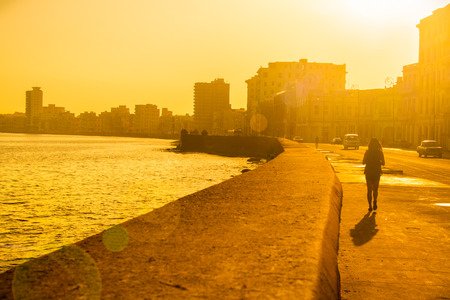 Backlit image of a colorful sunrise in Havana with a view of the malecon seawall and the city skylineの写真素材