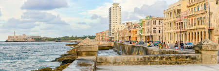 The Malecon seawall in Havana with a view of old buildings people and old carsのeditorial素材