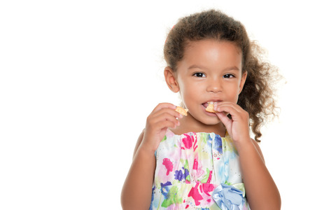 Cute small girl eating a cookie isolated on whiteの写真素材