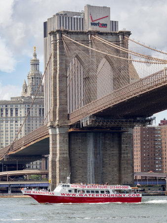 Sightseeing tour boat sailing under the Brooklyn Bridge in New York Cityのeditorial素材