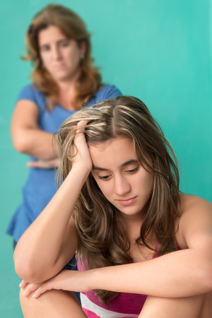 Sad and depressed teenage girl and her worried mother at homeの写真素材