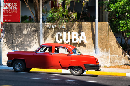 Old classic car crosses in front of sign with the word CUBAの写真素材