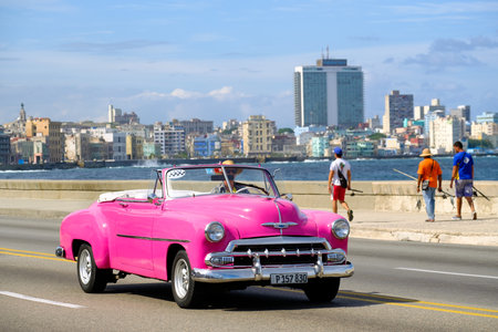 Classic american convertible car and fishermen at the famous seaside Malecon avenue in Havanaのeditorial素材
