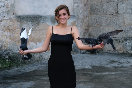 Beautiful smiling hispanic teenage girl carrying pigeons in her handsの写真素材