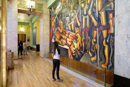 Visitor admiring a famous mural painting by David Alfaro Siqueiros at the museum of Palacio de Bellas Artes in Mexico Cityのeditorial素材