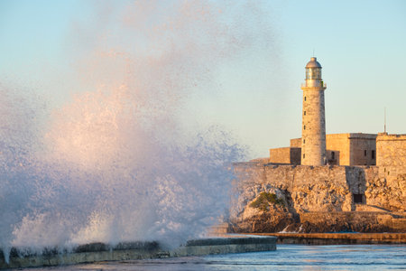 El morro fortress and lighthouse of Havana at sunset with huge sea waves crashing on the Malecon seawallのeditorial素材