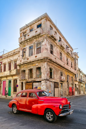 HAVANA,CUBA - FEBRUARY 3, 2016 : A vintage american car next to an crumbling old building in Havanaのeditorial素材