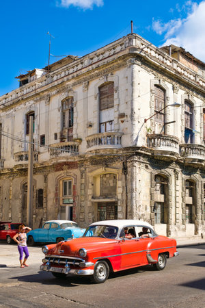 HAVANA,CUBA - FEBRUARY 3, 2016 : A vintage american car next to an crumbling old building in Havanaのeditorial素材
