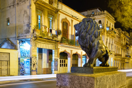 Night scene with the famous bronze lion and a view of the old houses along El Prado avenue in downtown Havanaのeditorial素材