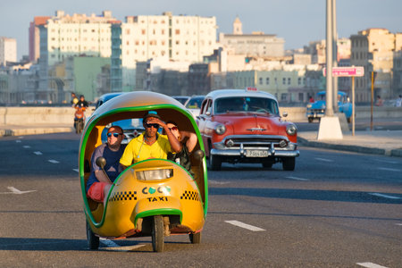 A typical cuban motorbike taxi known as cocotaxi travels along the Malecon seaside avenue in Havanaのeditorial素材