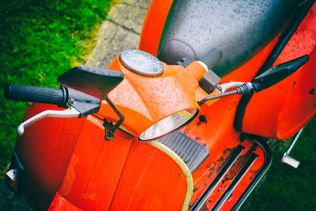 Vintage italian scooteVintage italian scooter painted in bright red on a green grass backgroundの写真素材