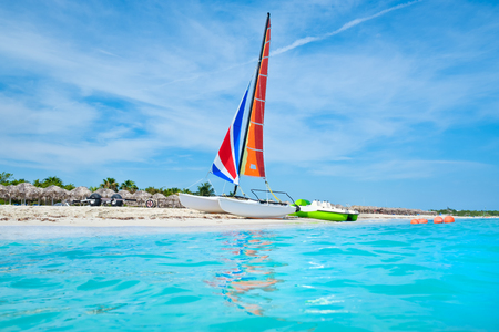 The beautiful beach of Varadero in Cuba with a colorful sailboat and turquoise waterの写真素材