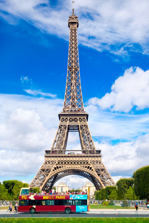 An open top tour bus stops in front of the Eiffel Tower in Paris on a sunny summer dayのeditorial素材