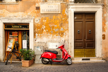 Typical street scene in Rome with a red scooter on an old narrow cobblestoned streetのeditorial素材