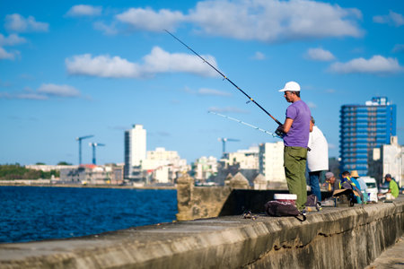 HAVANA,CUBA - NOVEMBER 6, 2017 : People fishing on the Malecon seawall in Havana with a view of the city skylineのeditorial素材