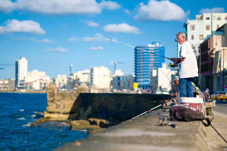HAVANA,CUBA - NOVEMBER 6, 2017 : People fishing on the Malecon seawall in Havana with a view of the city skylineのeditorial素材