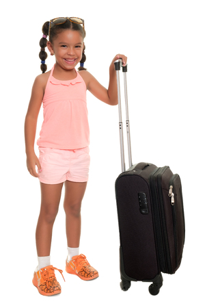 Cute multiracial small girl carrying a travel suitcase and smiling - Isolated on whiteの写真素材