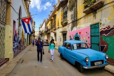 Street scene with cuban flags, old car and colorful aged buildings in Old Havanaのeditorial素材
