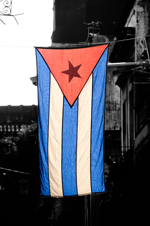 Colorful cuban flag  with a black and white aged Old Havana building on the backgroundの写真素材