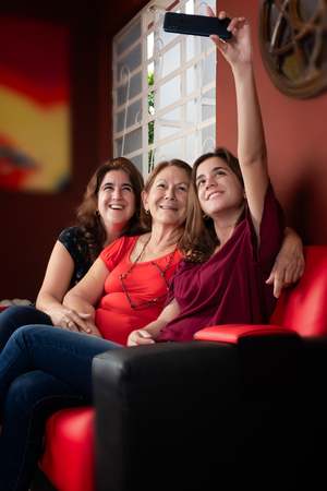 Three generations of hispanic women taking a selfie at homeの写真素材