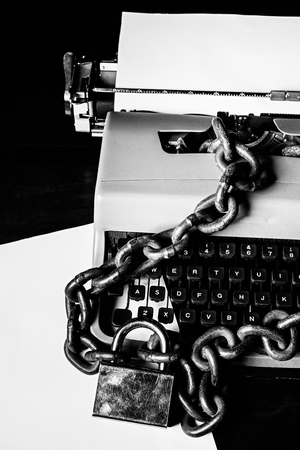 Information censorship concept - Typewriter locked with a chain and padlock - In black and white