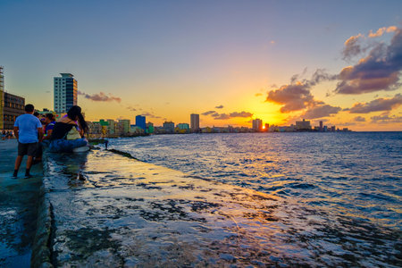 HAVANA,CUBA - FEBRUARY 9,2019 : People sitting on the malecon seawall in Havana during a beautiful sunset with a view of the city skylineのeditorial素材