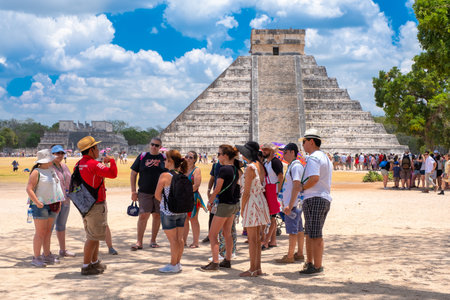 Tourists hear an explanation from their guide next to the Pyramid of Kukulkan at Chichen Itza