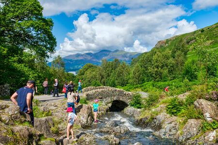 LAKE DISTRICT,ENGLAND - AUGUST 8,2019 : Tourists visiting the old Ashness Bridge on the Lake Districtの写真素材