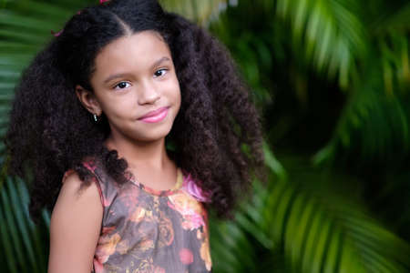 Portrait of a cute multiracial small girl with a green vegetation backgroundの写真素材