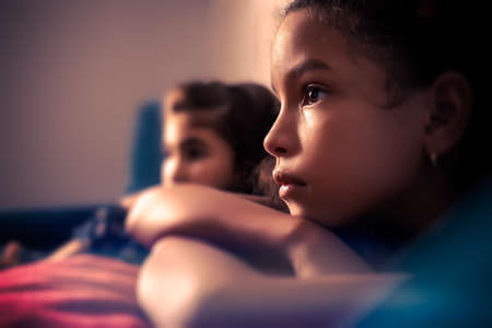 Portrait of two small girls watching TV - with a shallow depth of fieldの写真素材