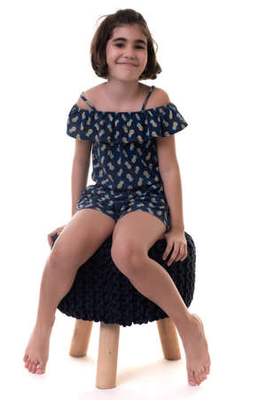 Cute hispanic girl sitting on a stool seat - Isolated on a white backgroundの写真素材