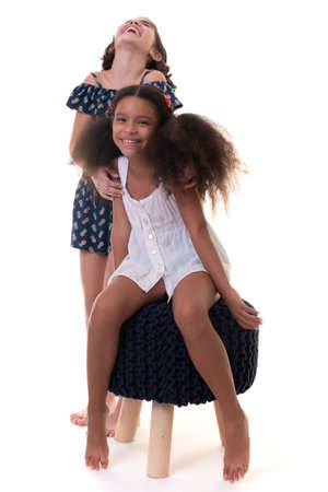 Two friendly small girls laughing , friends or sisters  - Hispanic and african-american - Isolated on whiteの写真素材
