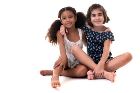 Two friendly small girls hugging  - Hispanic and african-american - Isolated on whiteの写真素材