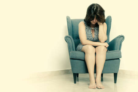 Stressed and sad  woman sitting alone on a chair - With space for textの写真素材