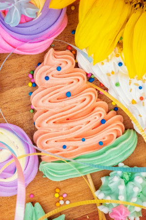 Collection of colorful meringues on a wooden background with sunflowers