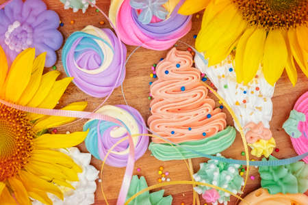 Collection of colorful meringues on a wooden background with sunflowersの写真素材