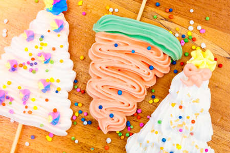 Christmas tree shaped meringue lollipops on a wood background