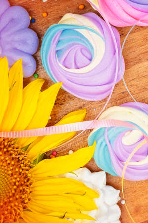 Collection of colorful meringues on a wooden background with sunflowersの写真素材