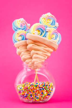 Colorful ice cream shaped meringue lollipops on a bright pink backgoundの写真素材