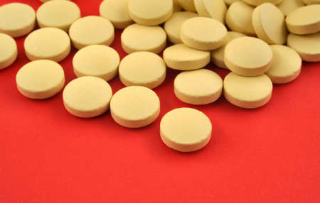 handful of yellow tablets on red #3の写真素材