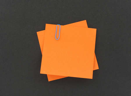 two post-it notes with a paperclip on black background