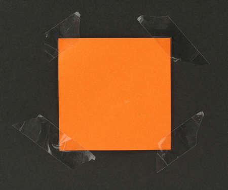 orange post-it stuck to a blackboard with tapeの写真素材