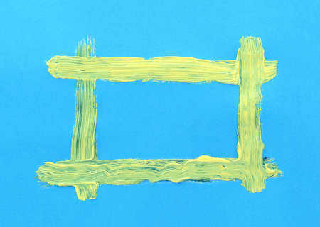 yellow handpainted frame on bright blue paperの写真素材