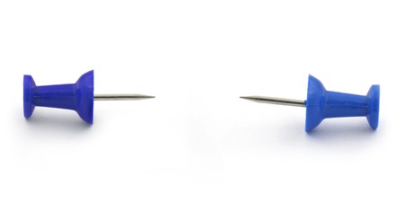two thumbtacks on white, metaphor of being trapped betweend claws
