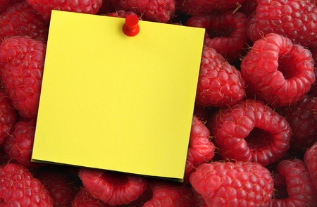 beautiful ripe juicy raspberries and yellow paper note