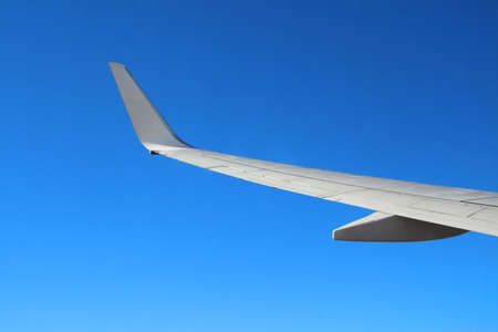 wing of a plane flying above cloudless skyの写真素材