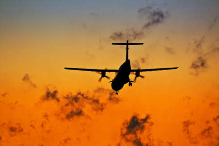 Sunset scene with silhouette of a landing plane